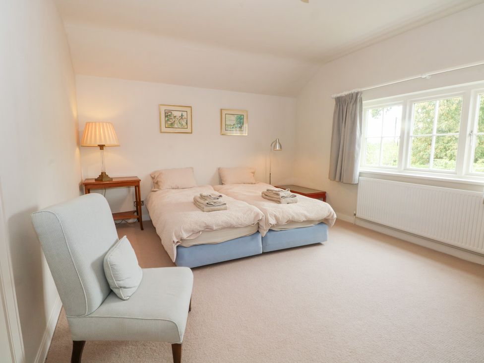 A bedroom with two beds and a chair at Higher Park Farm in Alderley Edge