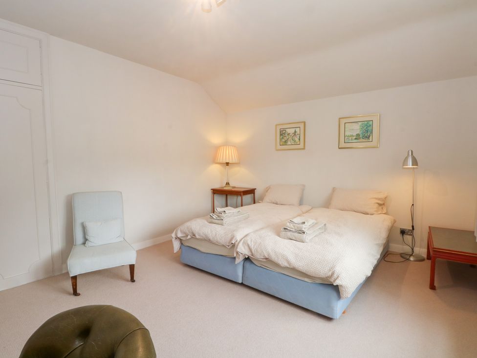 A bedroom with two beds and a chair at Higher Park Farm in Alderley Edge