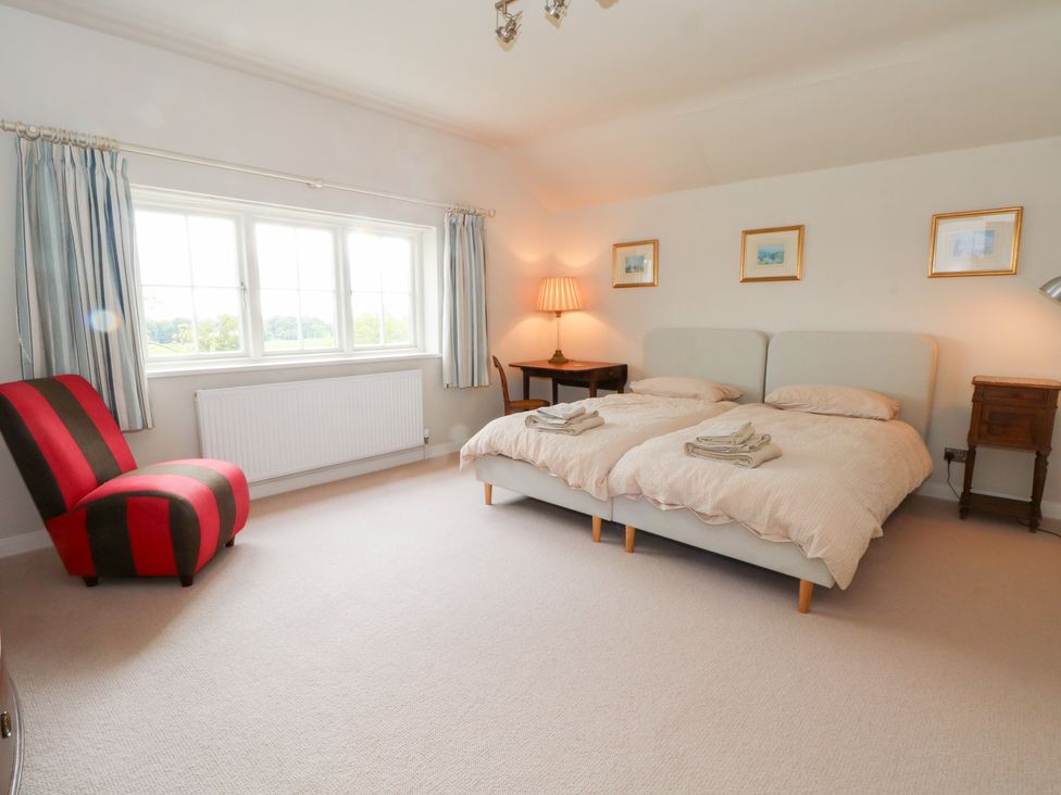 A bedroom with twin beds and a chair at Higher Park Farm in Alderley Edge