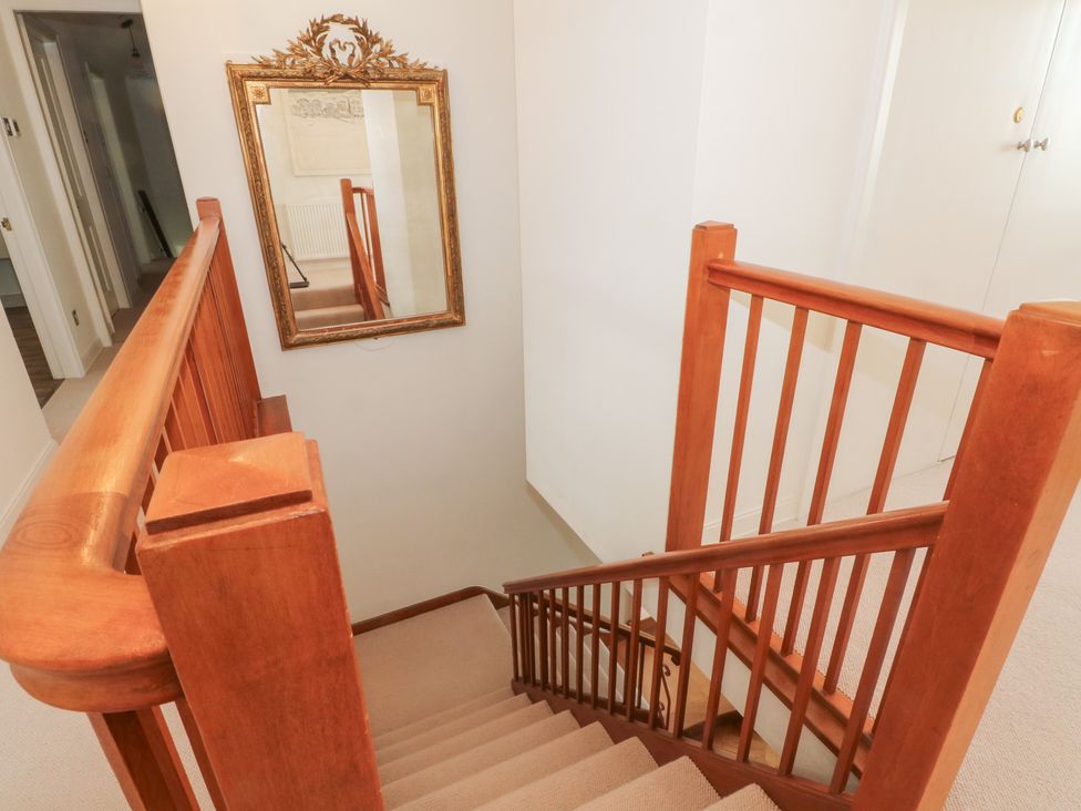 A staircase with a wooden handrail and mirror at Higher Park Farm in Alderley Edge
