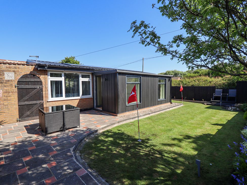 A backyard with a putting green, patio area with furniture, and a building at 19 The Court in Anderby Creek