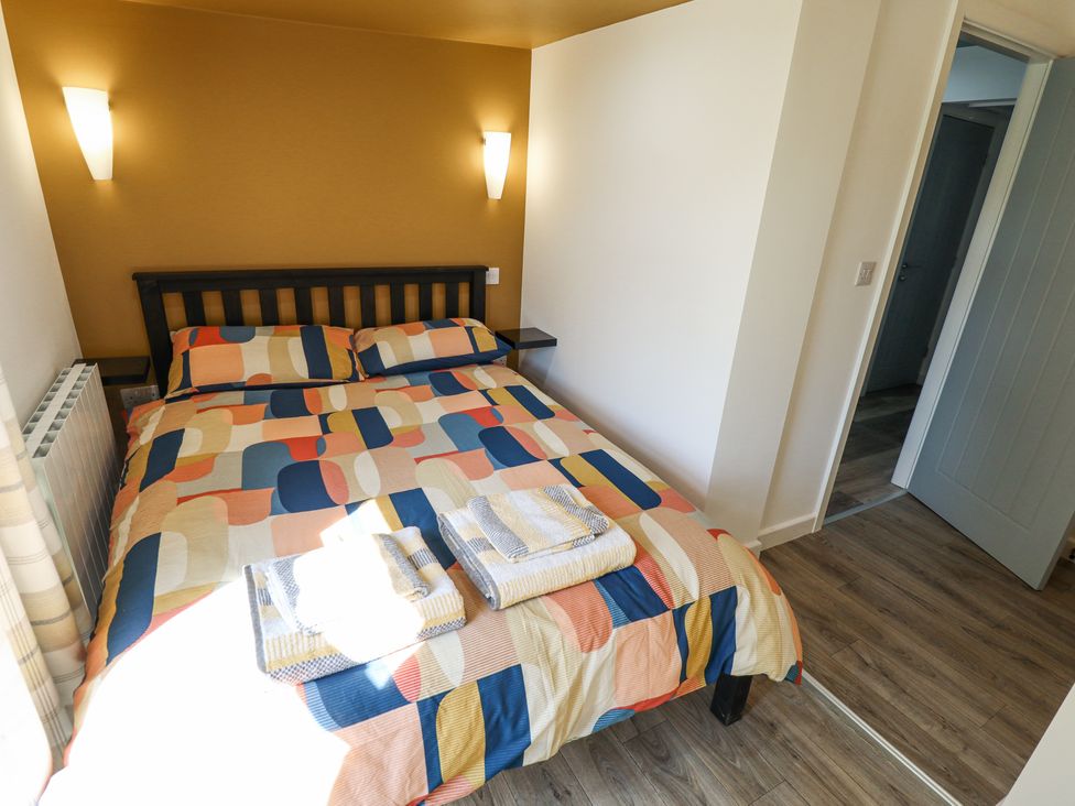 A bedroom with a double bed with multicolored bedding and towels on it at 19 The Court in Anderby Creek