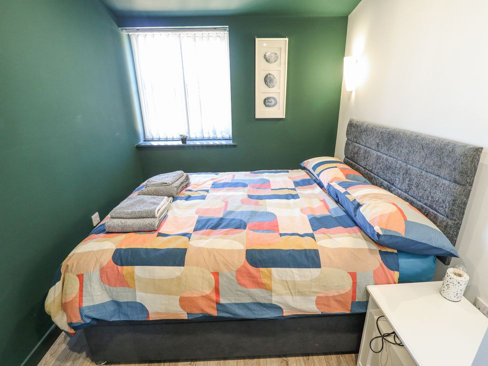 A bedroom with a bed with patterned bedding towels on the bed a window with blinds and a nightstand at 19 The Court in Anderby Creek
