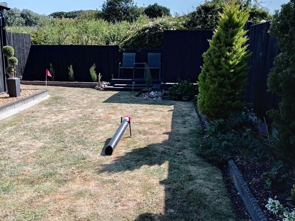 A garden with grass and lounge chairs at 19 The Court in Anderby Creek