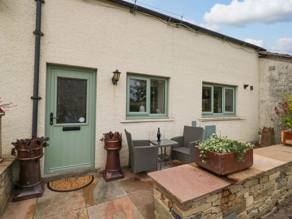 An outdoor seating area with a table and chairs at Yeat Stoup Cottage in Cockermouth