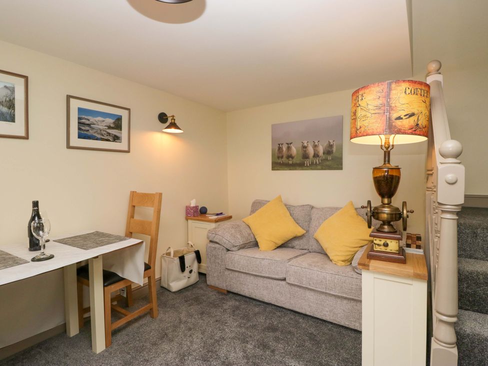 A snug room with a sofa and table at Yeat Stoup Cottage in Cockermouth