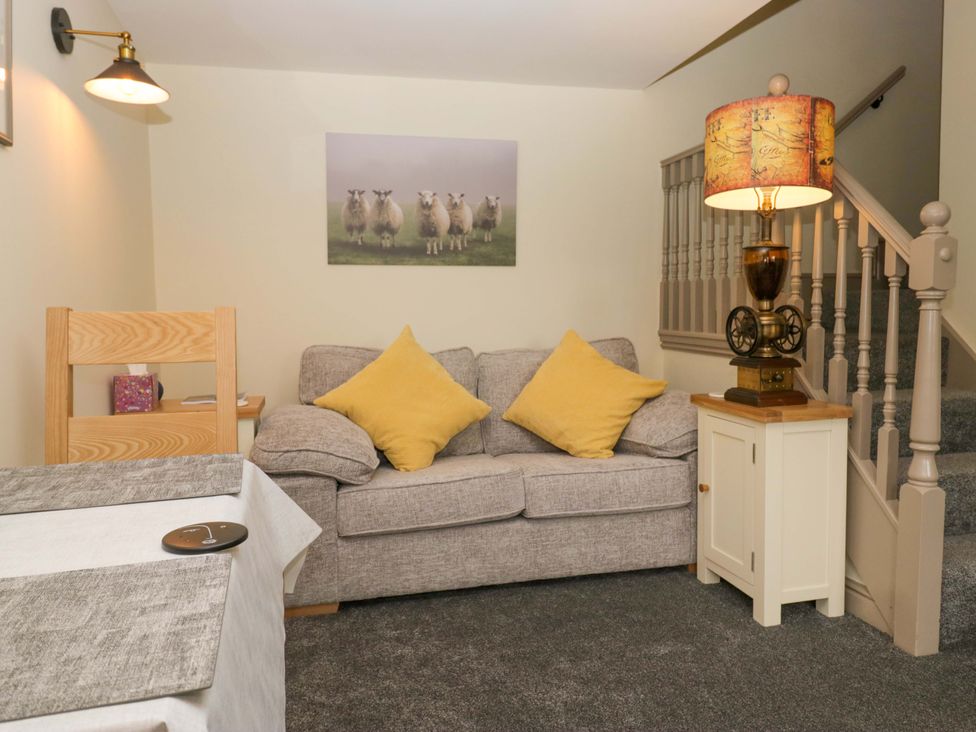 A living room with a sofa and staircase at Yeat Stoup Cottage Cockermouth