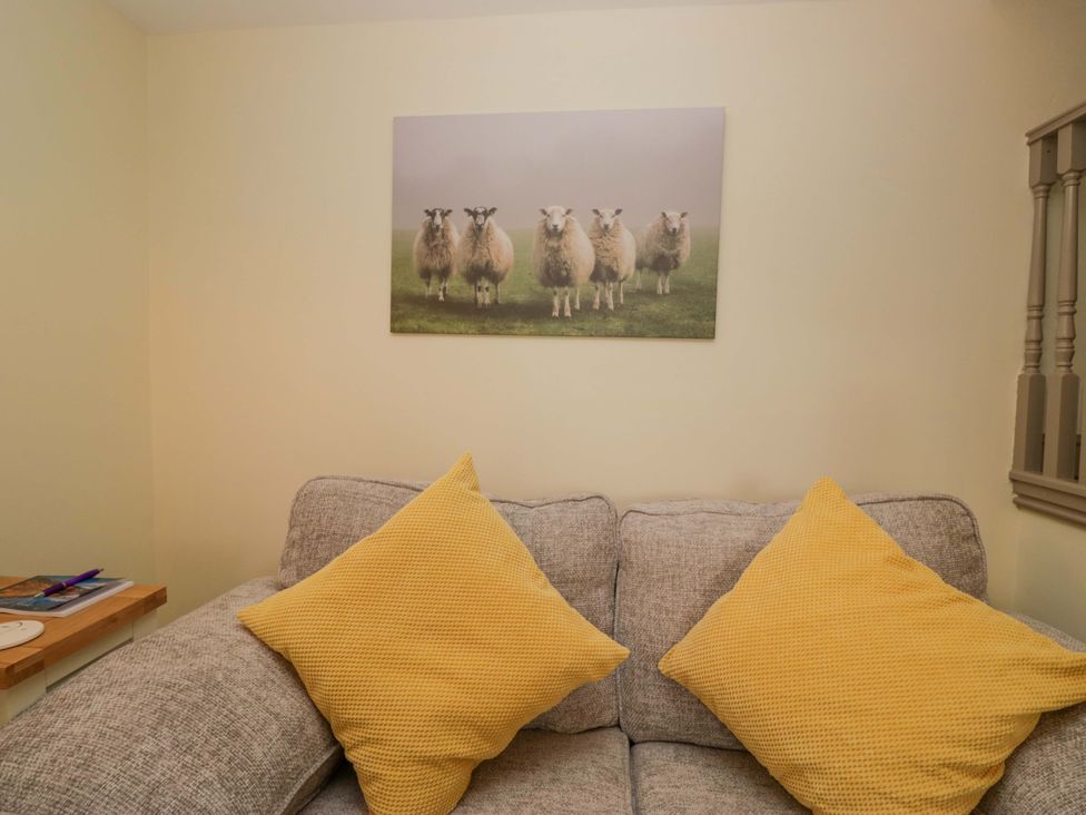 A living room with a sofa and wall art at Yeat Stoup Cottage in Cockermouth