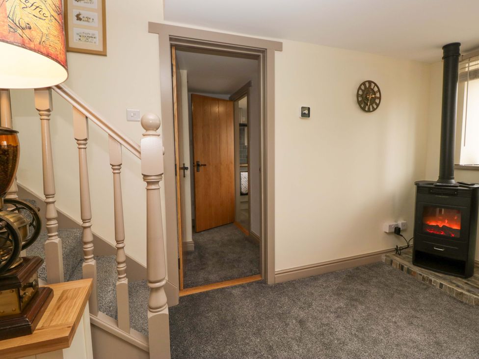 A hallway with a staircase and an electric fireplace at Yeat Stoup Cottage in Cockermouth