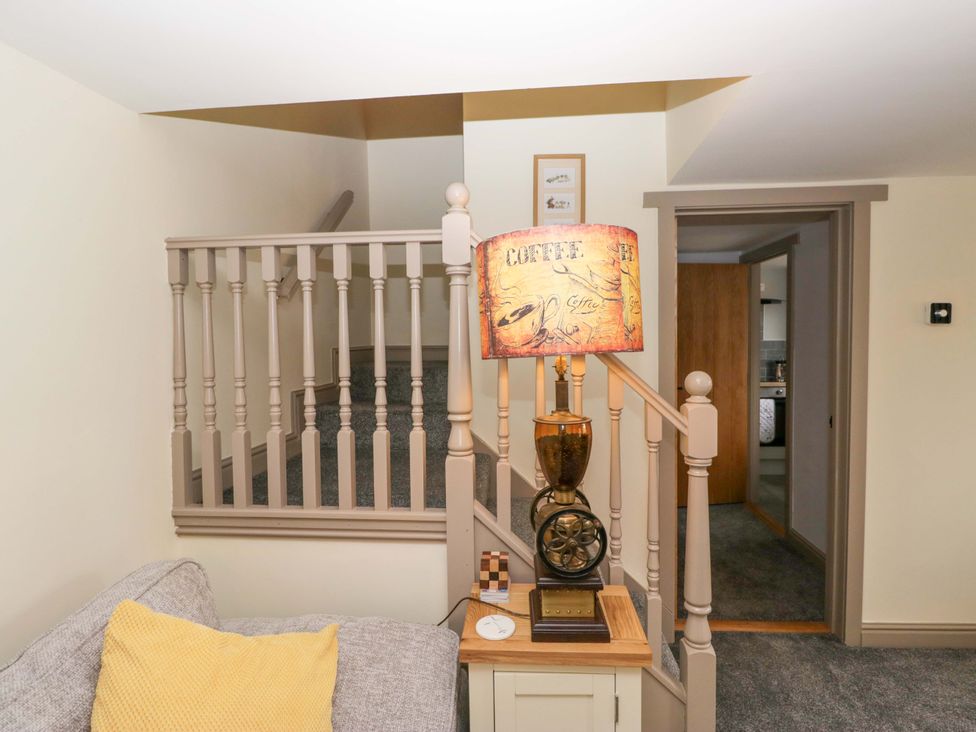 A hallway with a lamp and staircase at Yeat Stoup Cottage in Cockermouth