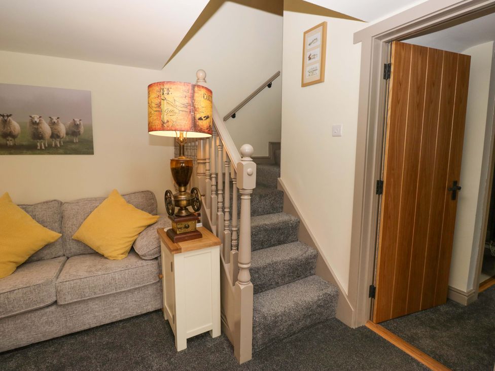 A hallway with a sofa and lamp at Yeat Stoup Cottage in Cockermouth