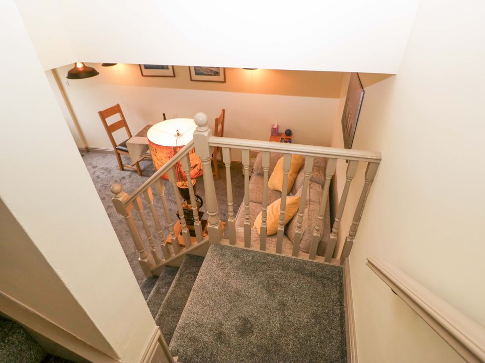 A staircase leading to a hallway with a table and sofa at Yeat Stoup Cottage Cockermouth