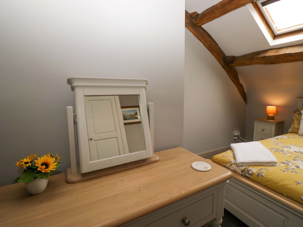 A bedroom with a mirror and a sunflower vase at Yeat Stoup Cottage in Cockermouth