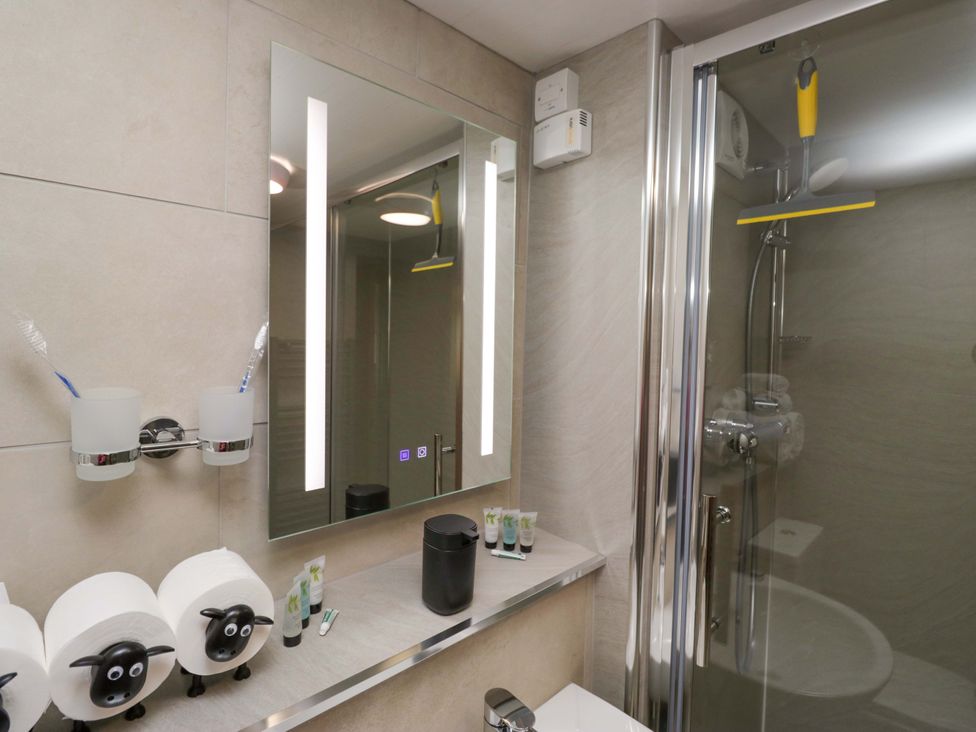 A bathroom with a shower and mirror at Yeat Stoup Cottage in Cockermouth