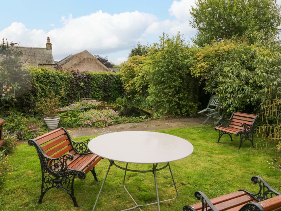 A garden with a table and chairs at Yeat Stoup Cottage in Cockermouth