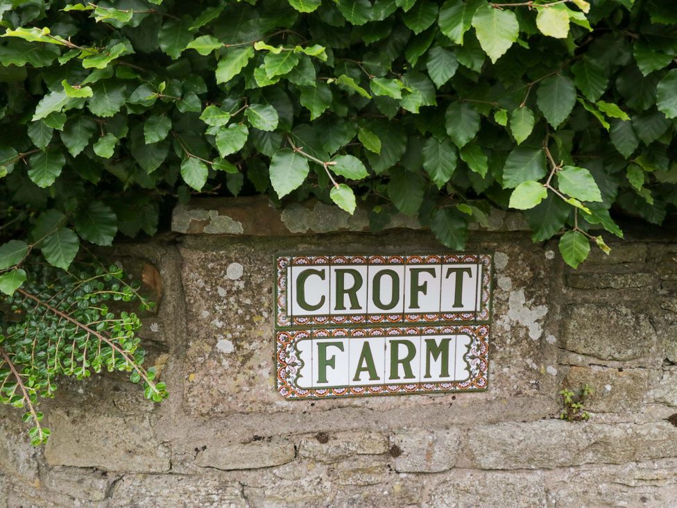 A sign labeled 'CROFT FARM' on a stone wall with greenery at Yeat Stoup Cottage in Cockermouth
