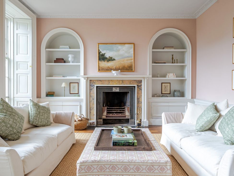 A living room with a fireplace and shelves at Batheaston House in Batheaston