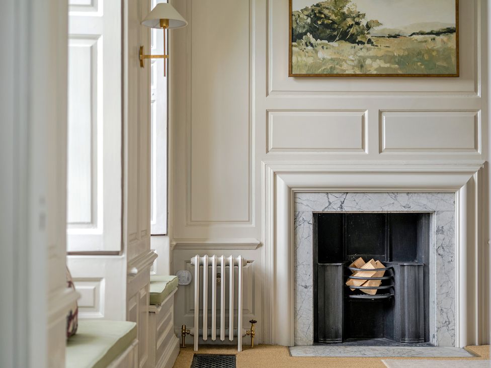 A living room with a fireplace and painting at Batheaston House Batheaston