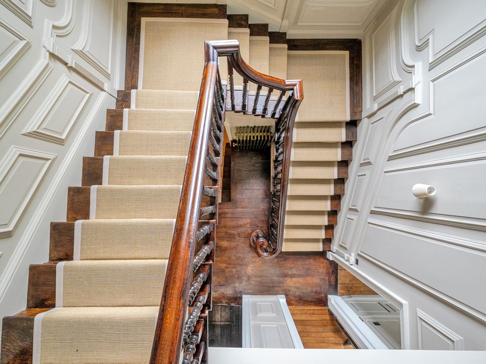 A staircase with a wooden handrail and walls at Batheaston House in Batheaston