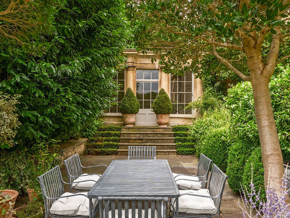 A garden with a dining table and chairs at Batheaston House in Batheaston