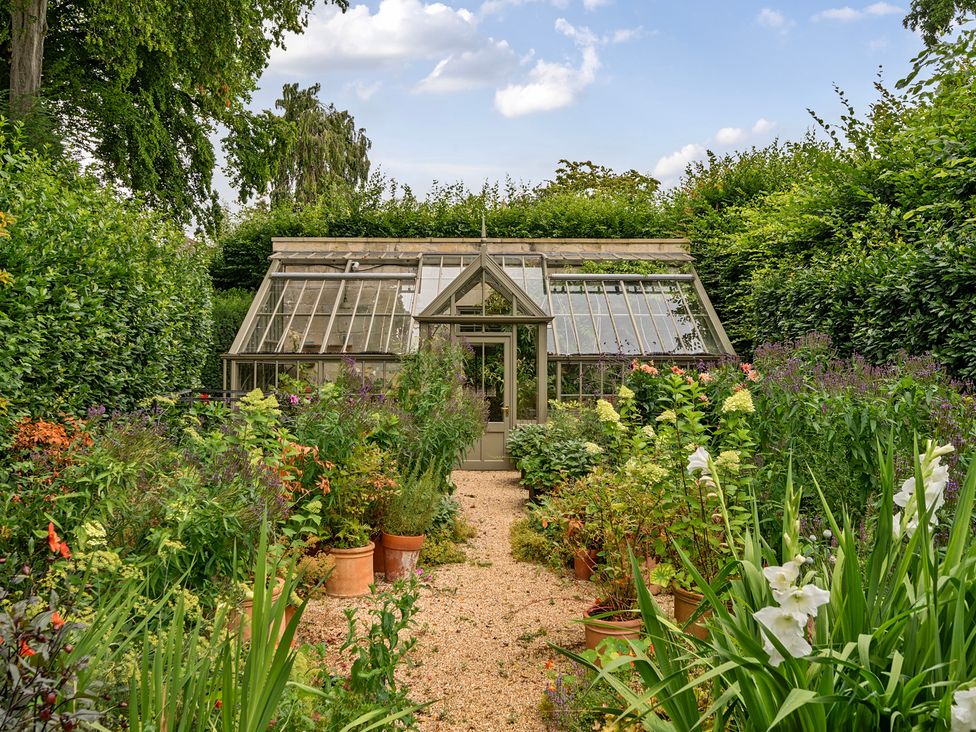 A greenhouse surrounded by flowers and plants in Batheaston House, Batheaston