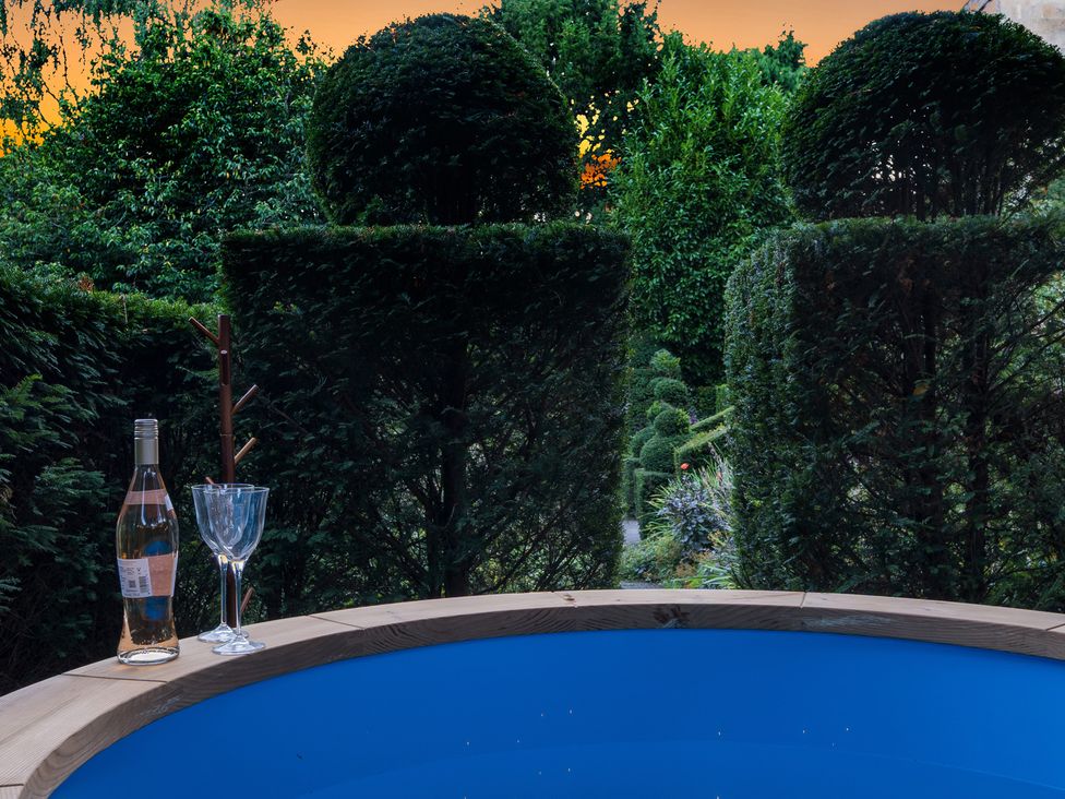 A hot tub with a wine bottle and glass at Batheaston House in Batheaston