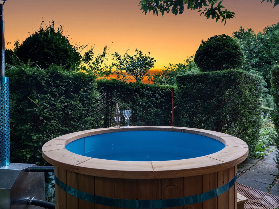A hot tub with a bottle and glasses at Batheaston House in Batheaston