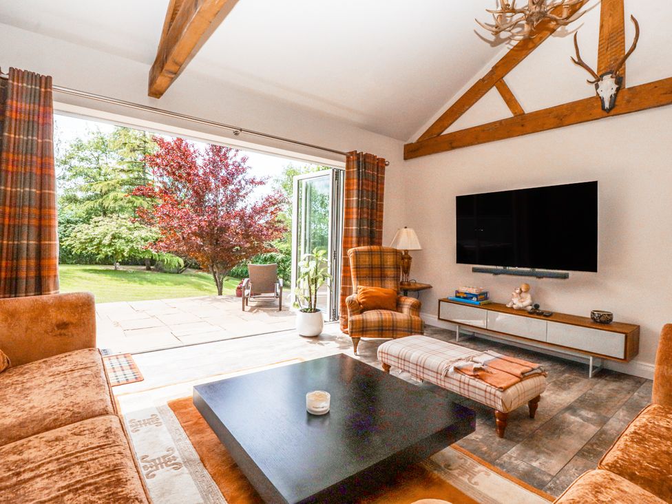 A living room with a sofa, coffee table, and television at The Old Coach House in Bilsborrow