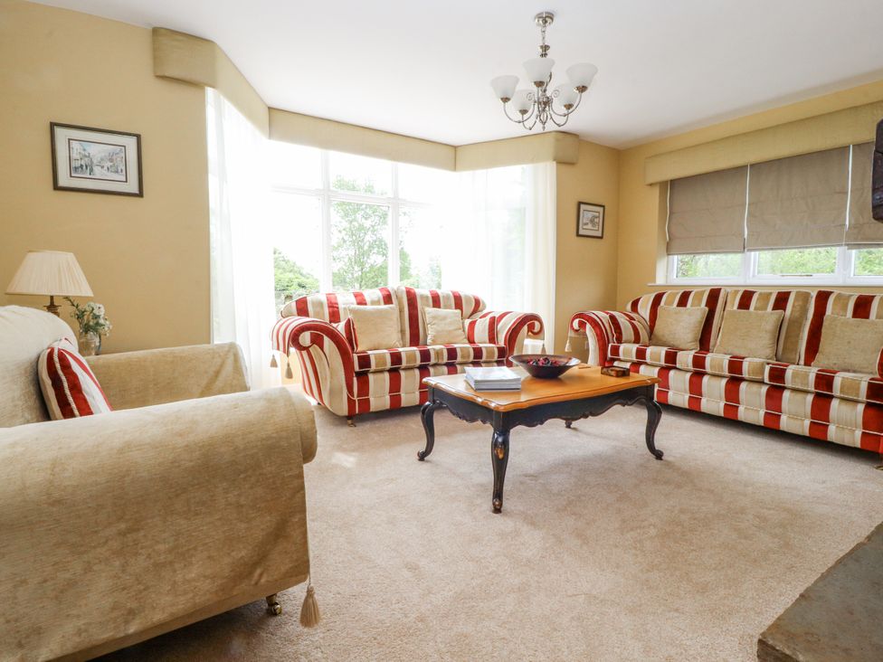 A living room with striped sofas and a coffee table at The Old Coach House in Bilsborrow