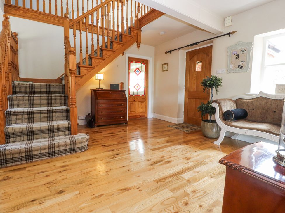 A hallway with stairs and a stained glass door at The Old Coach House in Bilsborrow