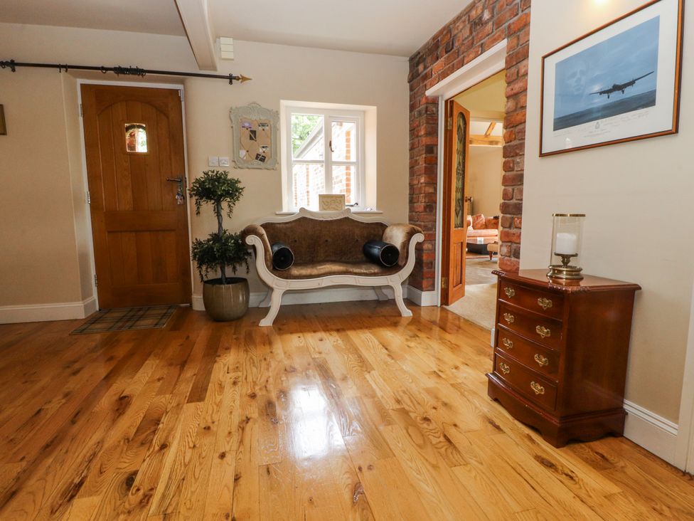 A hallway with a door, plant, seating, and console table at The Old Coach House in Bilsborrow