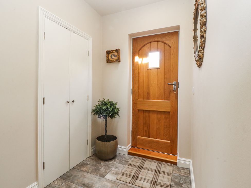 A hallway with a wooden door and indoor plant at The Old Coach House in Bilsborrow
