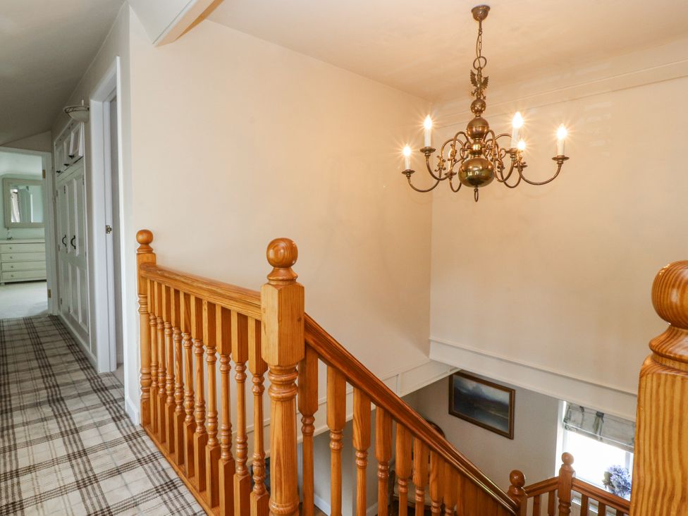 A staircase with a chandelier in the hallway at The Old Coach House in Bilsborrow