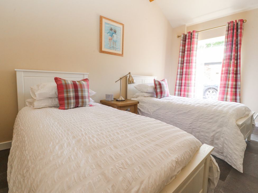 A bedroom with two beds and a bedside table at The Old Coach House in Bilsborrow