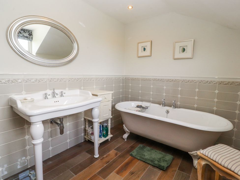 A bathroom with a sink, bathtub, and mirror at The Old Coach House in Bilsborrow