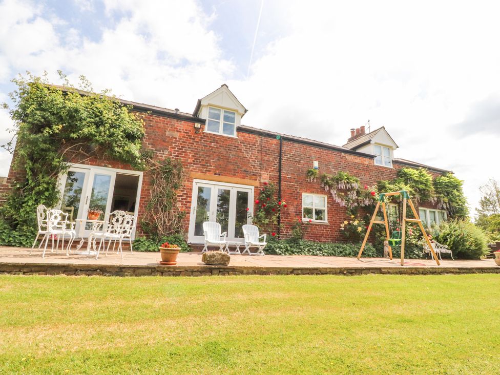 A house with a patio and garden furniture at The Old Coach House in Bilsborrow