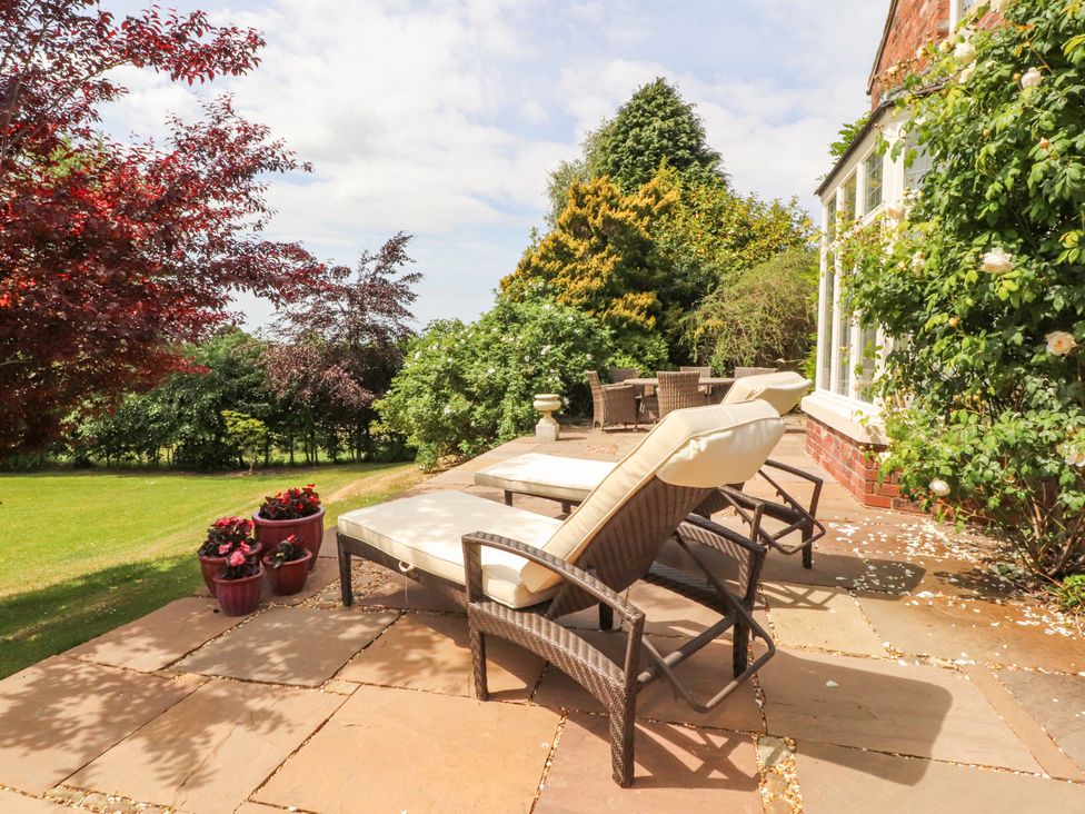 An outdoor seating area with chaise lounge and table at The Old Coach House in Bilsborrow