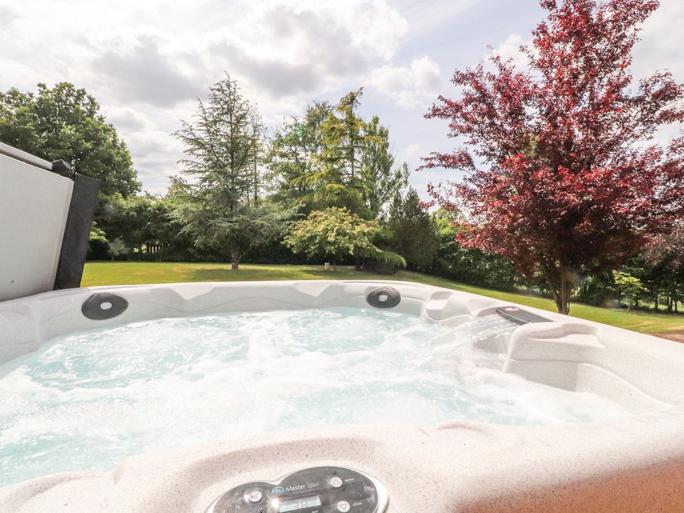 A hot tub with bubbling water surrounded by trees and grass at The Old Coach House in Bilsborrow