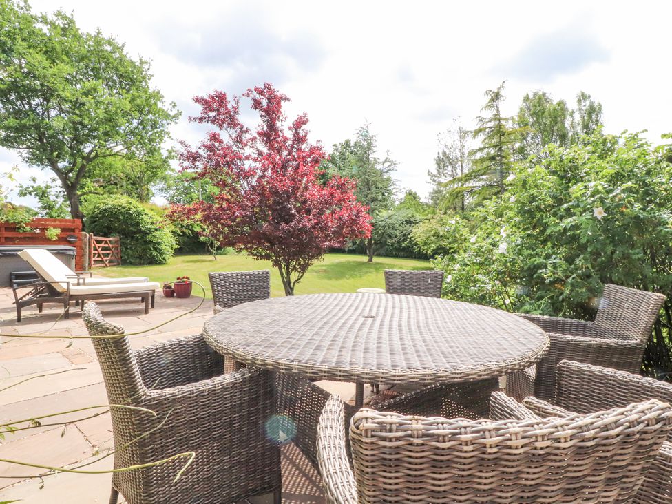A garden with a table and chairs and trees at The Old Coach House in Bilsborrow