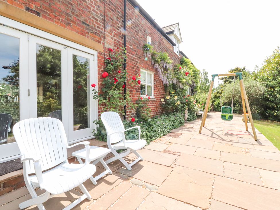 An outdoor area with white chairs and a swing at The Old Coach House in Bilsborrow