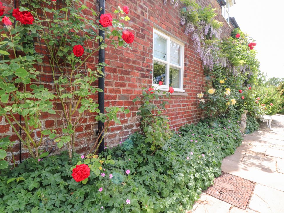 An outdoor area with flowers and a brick wall at The Old Coach House in Bilsborrow
