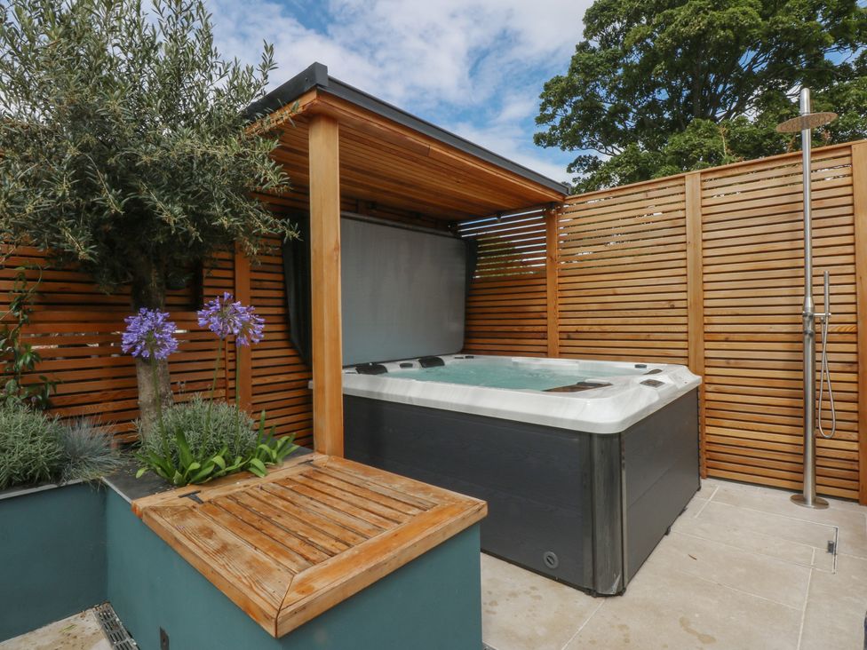 A hot tub and wooden seating area in the garden at Hilltop Cottage Conwy