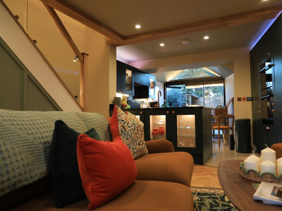 A living room with a sofa and kitchen in the background at Hilltop Cottage in Conwy