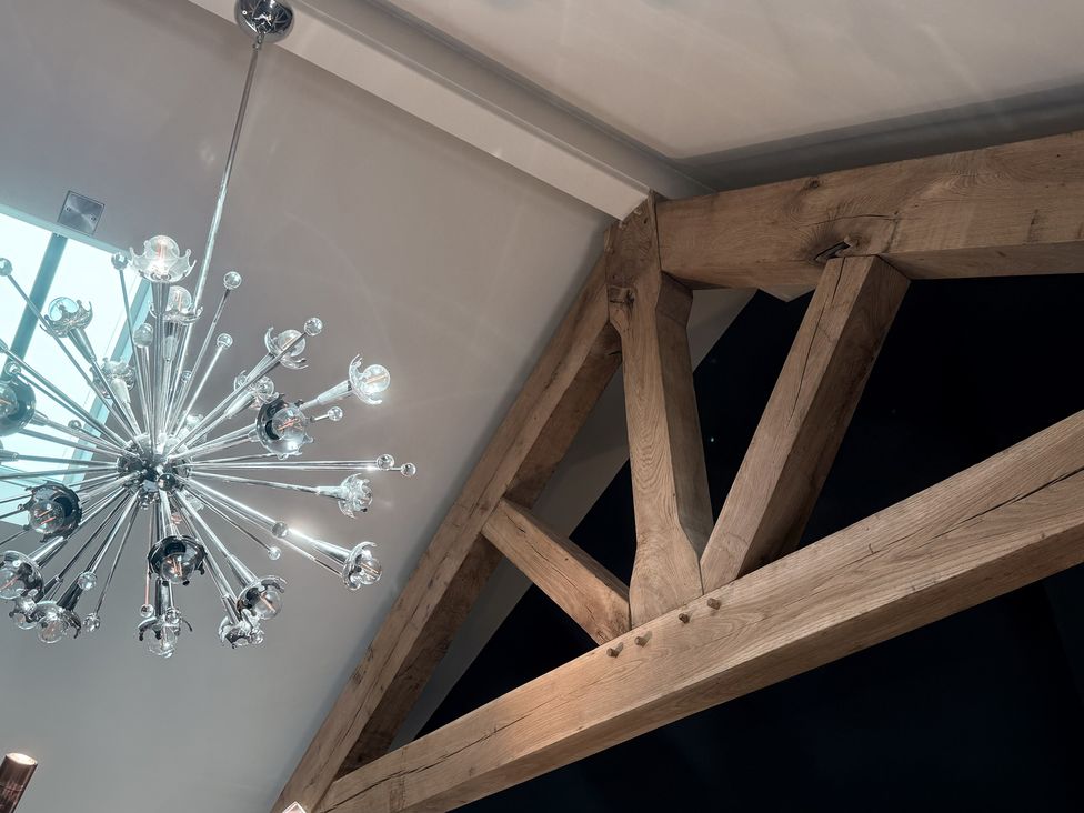 A chandelier and wooden beams in a room at Hilltop Cottage Conwy