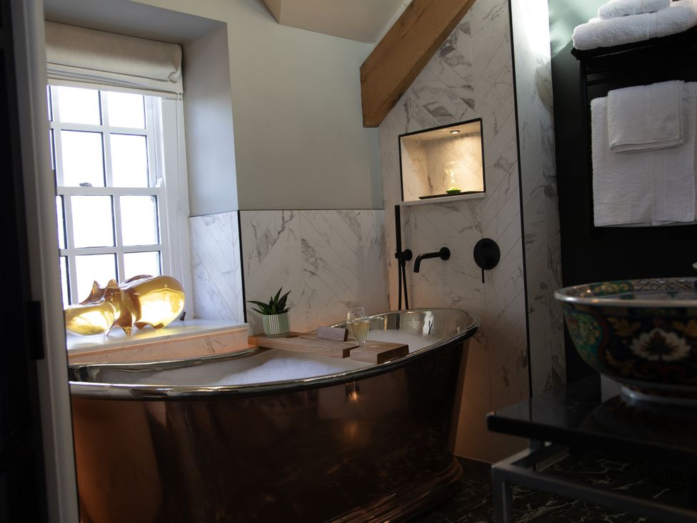 A bathroom with a bathtub and window at Hilltop Cottage in Conwy