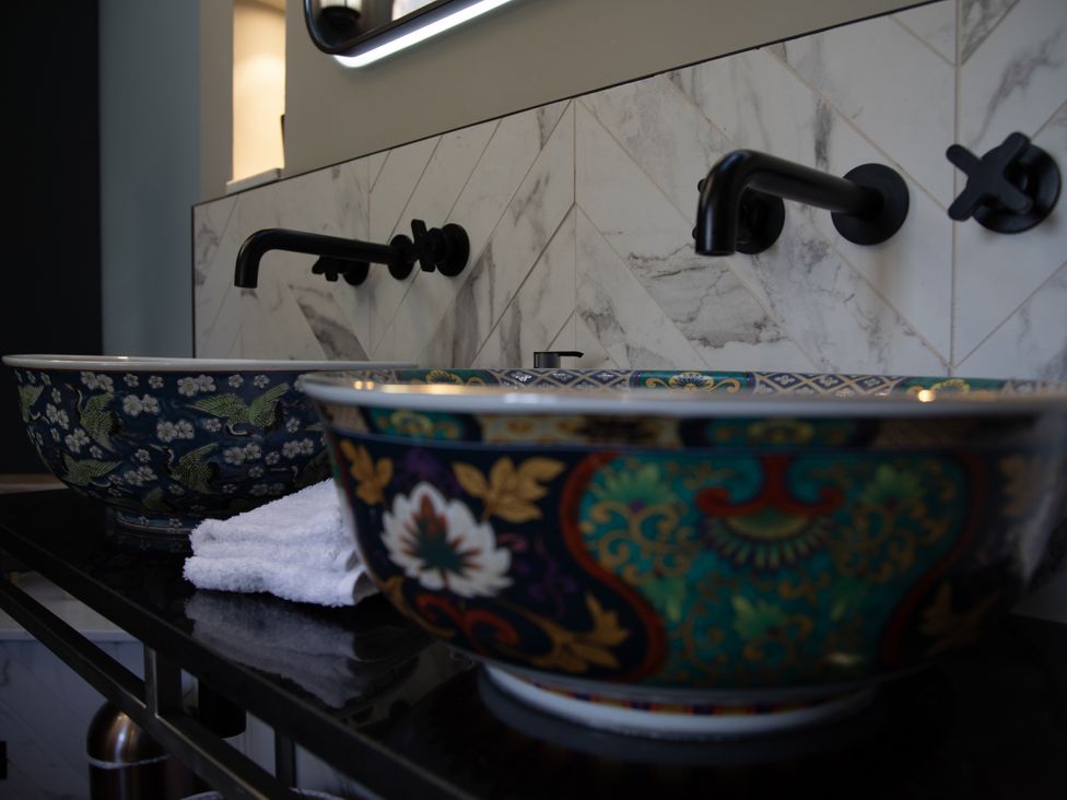 A bathroom with two wash basins and black faucets at Hilltop Cottage in Conwy