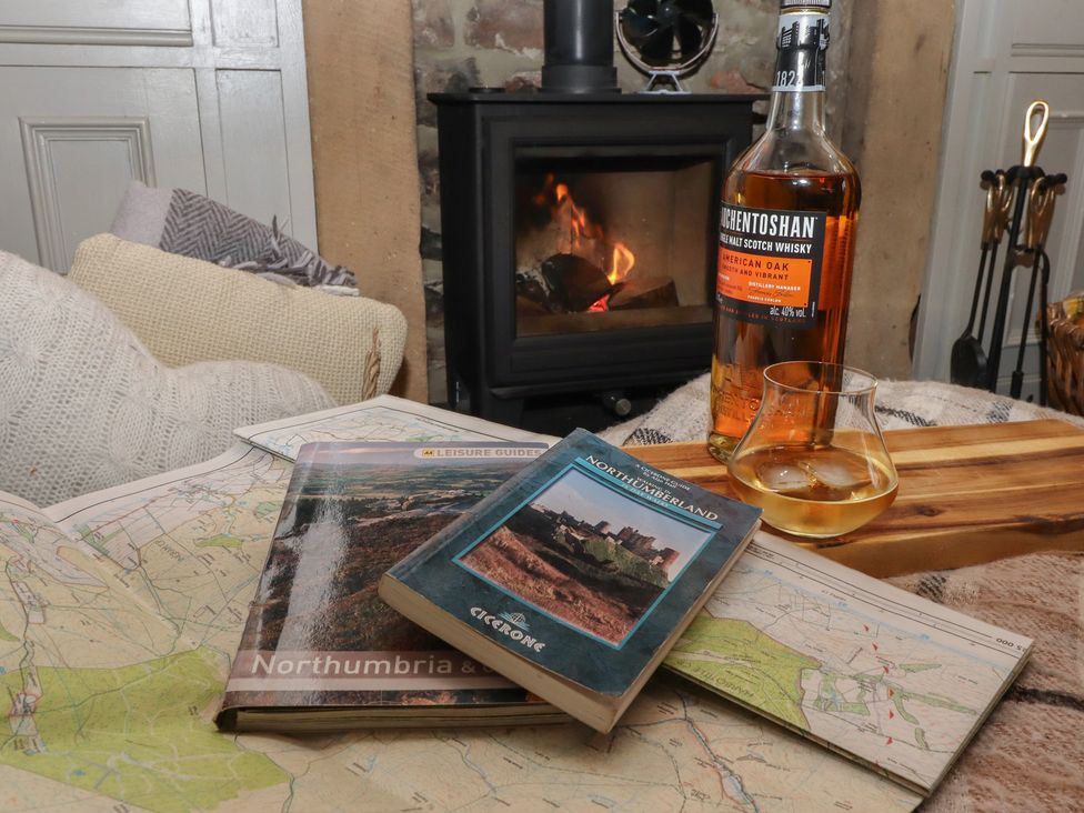 A living room with a whiskey glass and books at The Poachers Pocket in Whittingham near Powburn