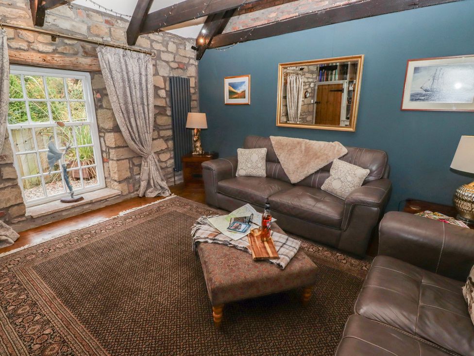 A living room with a window, sofa, coffee table, and decorative items at The Poachers Pocket in Whittingham near Powburn