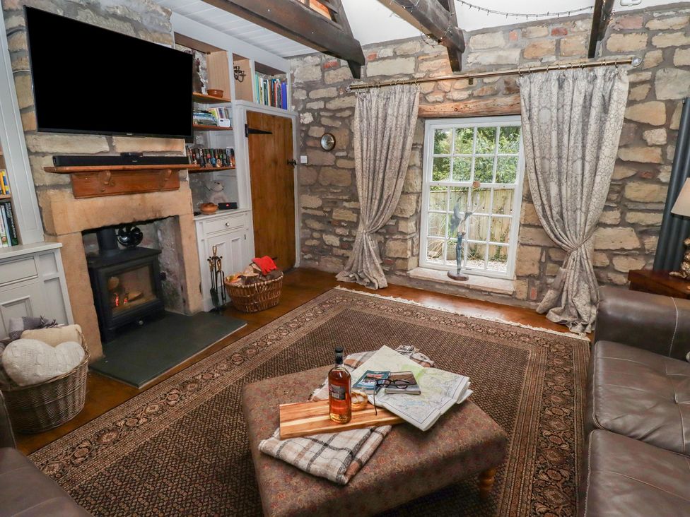 A living room with a fireplace and sofa at The Poachers Pocket in Whittingham near Powburn
