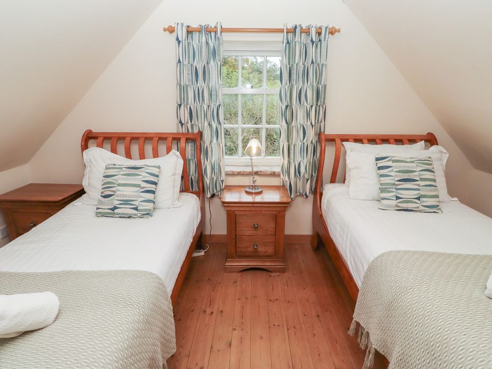 A bedroom with two single beds and a bedside table at The Poachers Pocket in Whittingham near Powburn